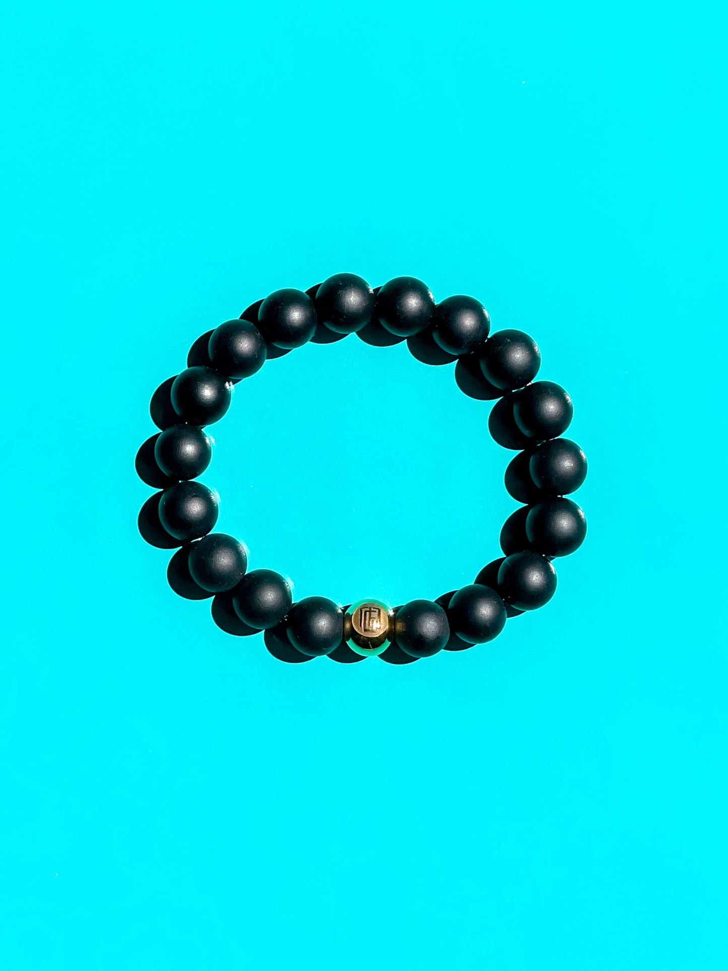 Men’s Bracelet with Matte Onyx and Gold plated over Stainless Steel logo bead.